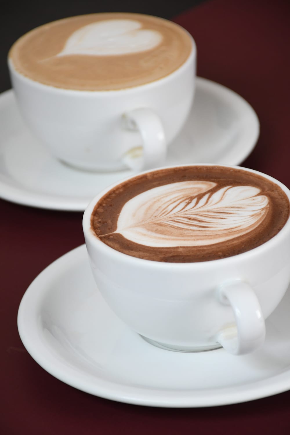 Dos capuchinos con arte latte servidos en taza blanca