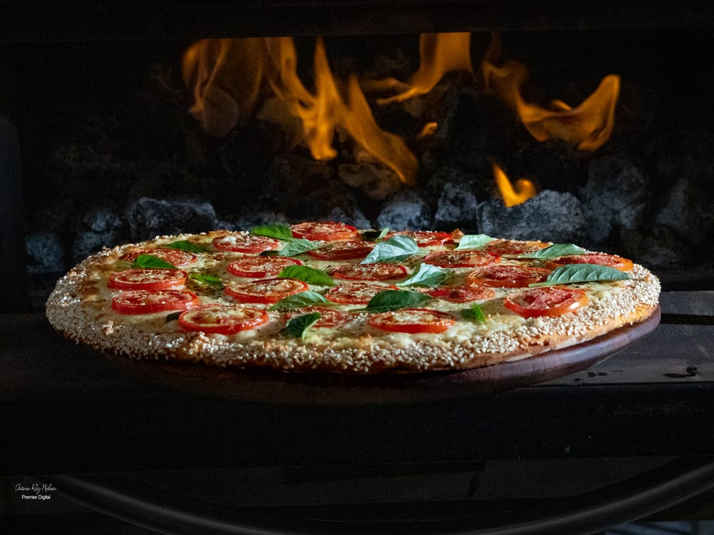 Pizza margarita frente al horno de leña encendido